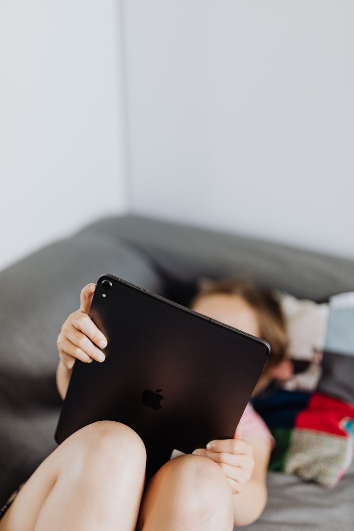 A child enjoying leisure time with a tablet indoors, focusing on digital interaction.